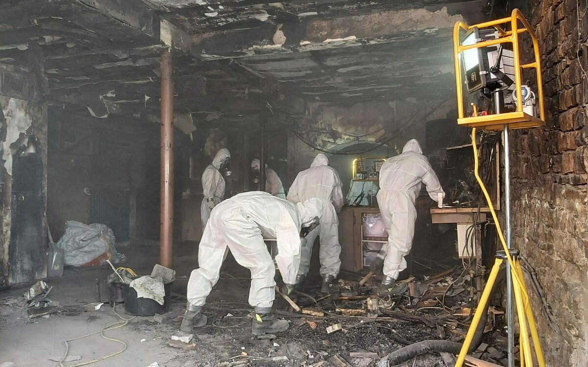 Feuerwehrleute mit schutzanzuegen am ausraeumen Feuerwehrleute mit schutzanzuegen am ausraeumen